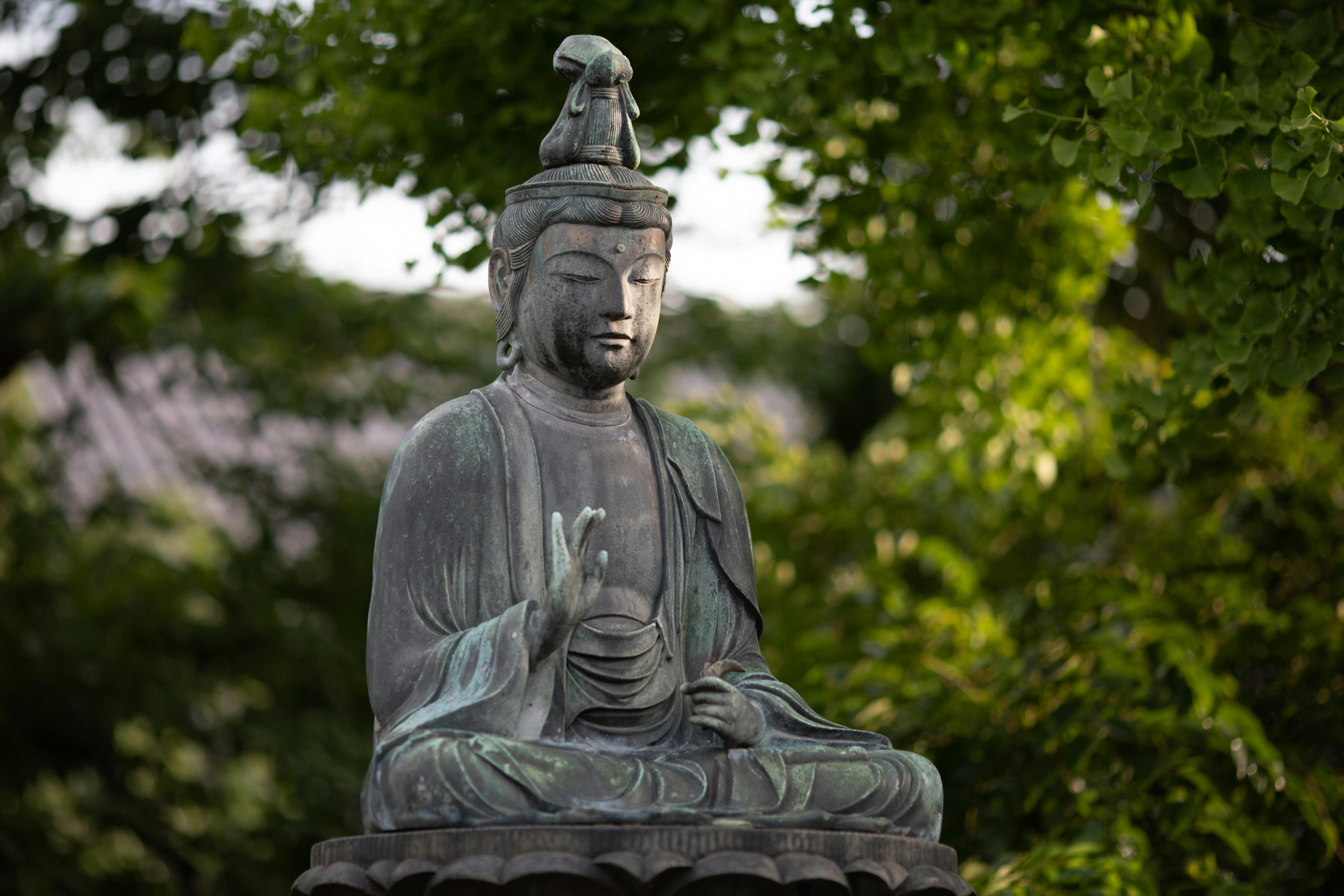 Buddha statue amidst lush greenery in Tokyo's Shinjuku City.