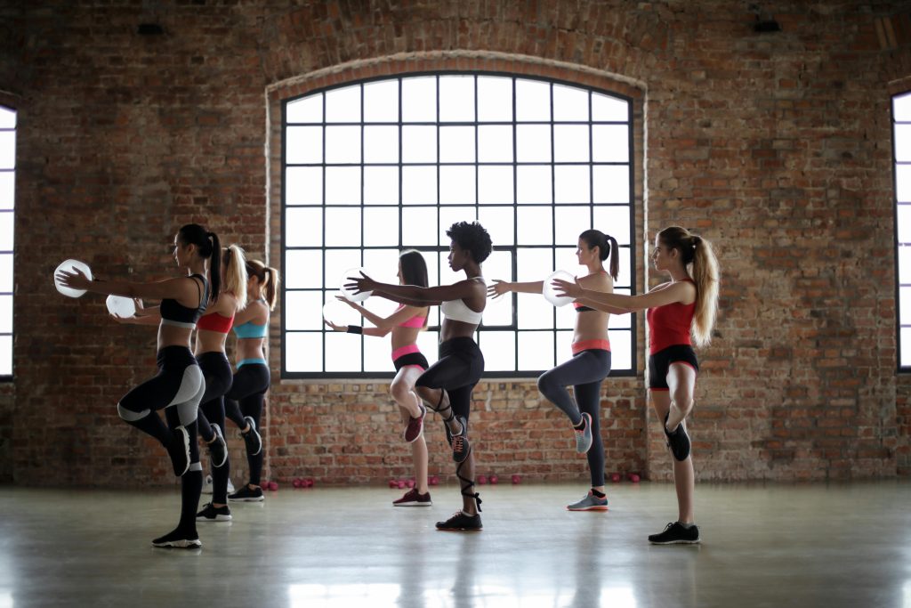 Women practicing yoga poses in a brick-walled studio, promoting fitness and flexibility.