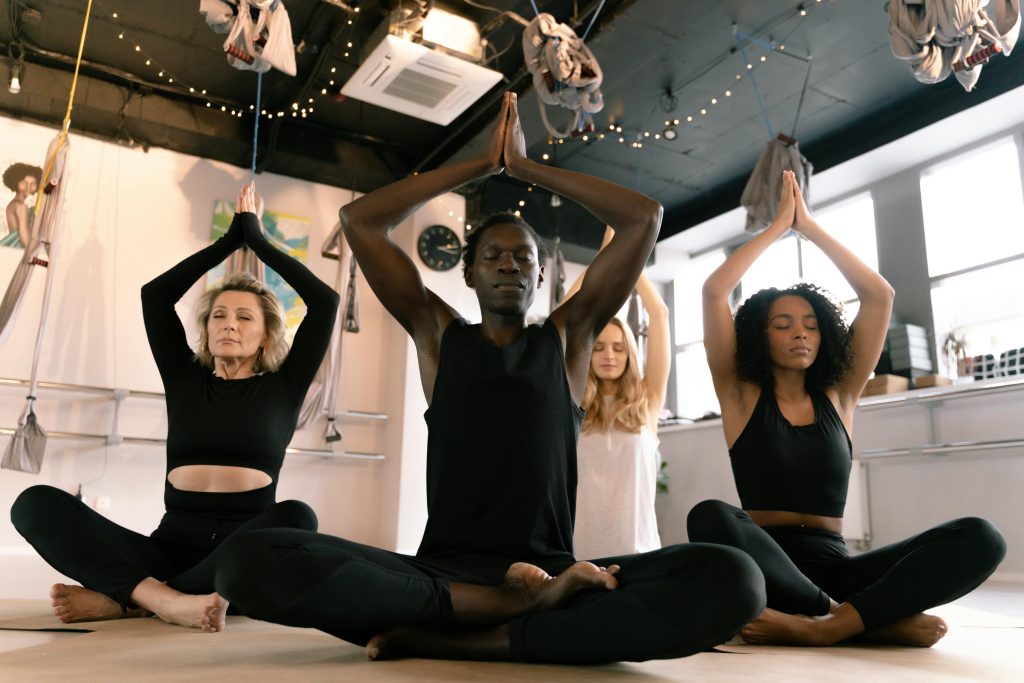 A diverse group of adults meditating in a yoga class indoors, focusing on mindfulness.