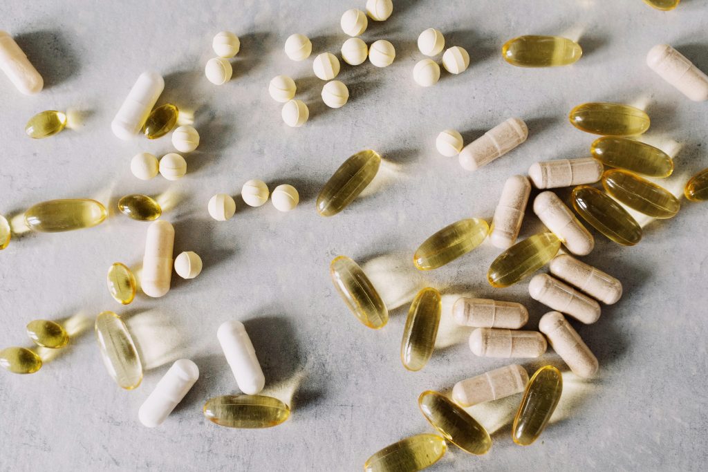 Various vitamins and supplements on a marble background, captured in flat lay style.
